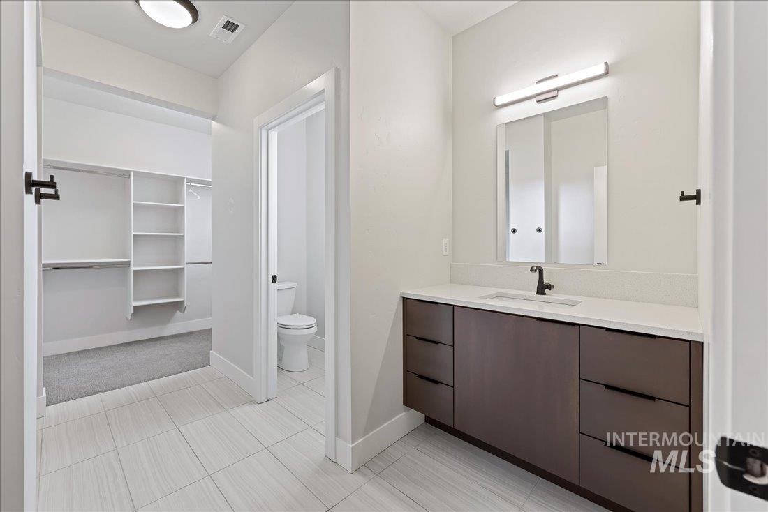 Bathroom featuring a walk in closet, vanity, and light tile patterned floors