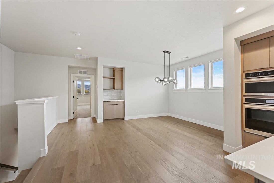 Kitchen featuring healthy amount of natural light, light wood-style floors, double oven, decorative backsplash, and recessed lighting