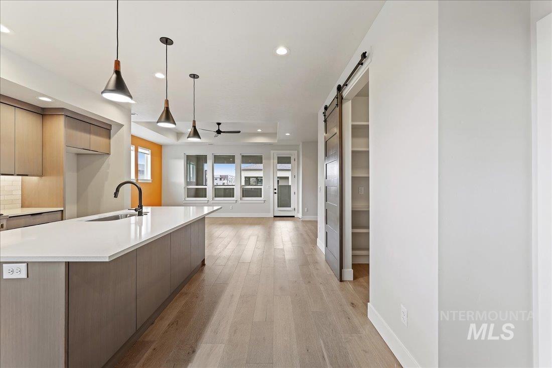 Kitchen with modern cabinets, light wood-type flooring, a barn door, pendant lighting, and recessed lighting