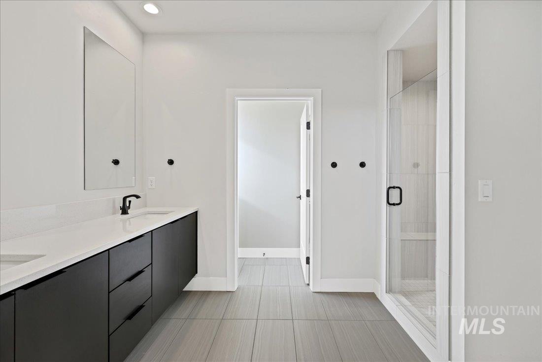Full bathroom featuring double vanity, a stall shower, recessed lighting, and light tile patterned floors