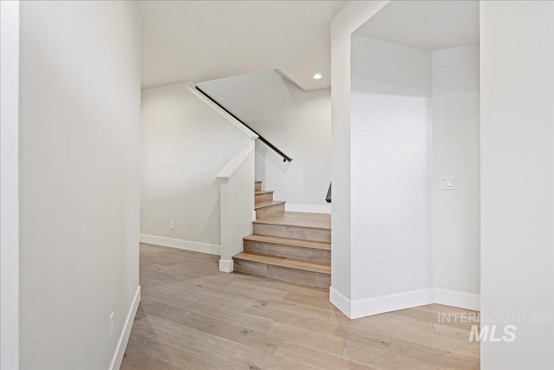 Stairway featuring wood finished floors and recessed lighting