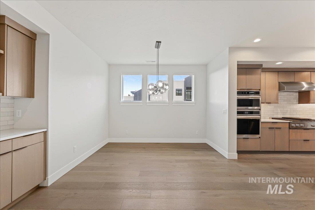 Kitchen with decorative backsplash, modern cabinets, light wood-type flooring, recessed lighting, and light brown cabinetry