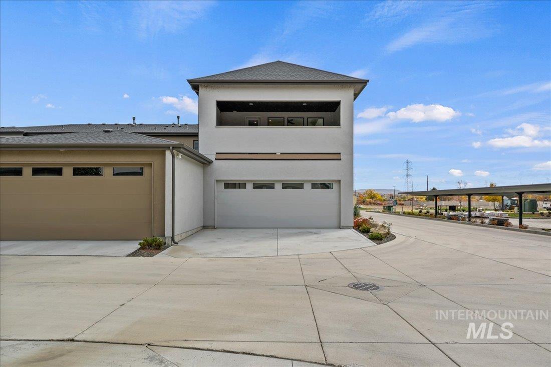 View of front facade with stucco siding, a garage, concrete driveway, a balcony, and a shingled roof