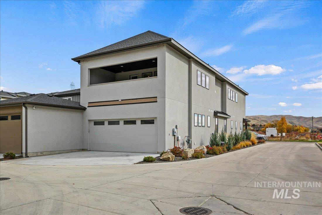 View of home's exterior featuring concrete driveway, stucco siding, a mountain view, and an attached garage