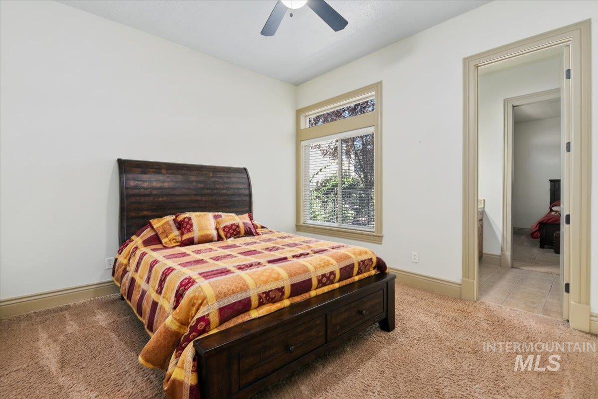 Bedroom with light colored carpet, a ceiling fan, ensuite bath, and light tile patterned floors
