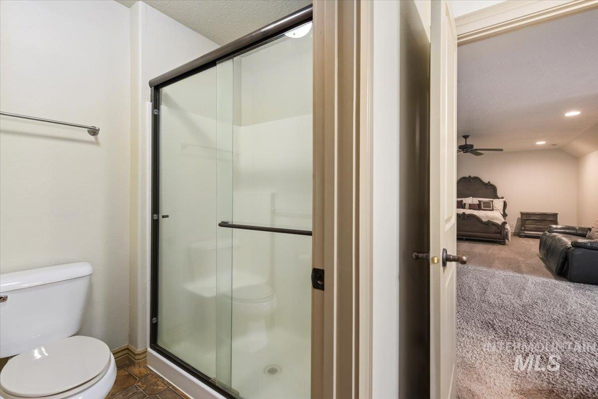 Ensuite bathroom with a stall shower, a textured ceiling, recessed lighting, and a ceiling fan