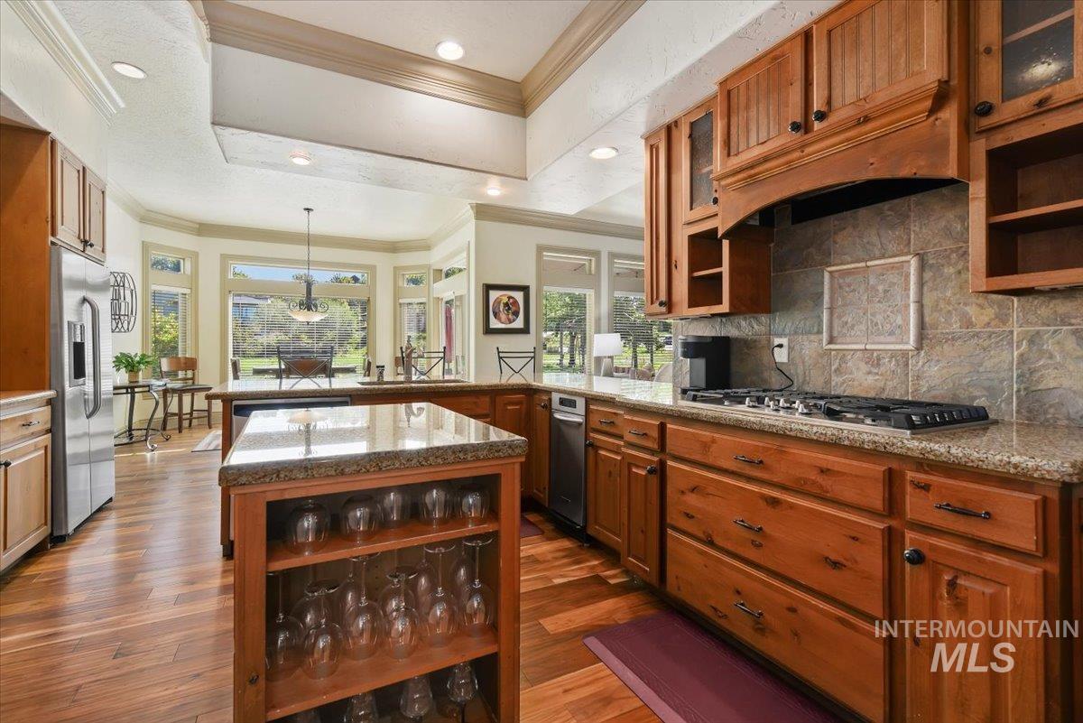 Kitchen featuring open shelves, crown molding, brown cabinetry, backsplash, and glass insert cabinets