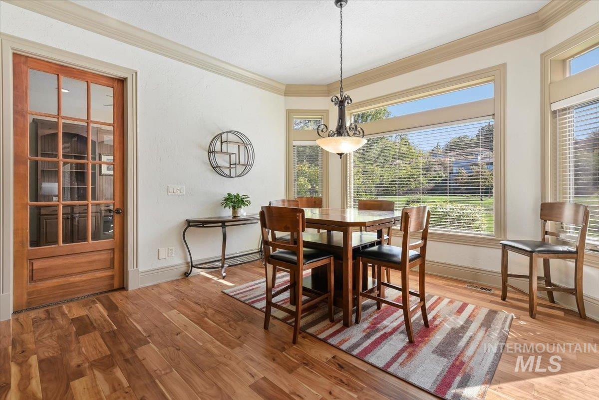 Dining area featuring ornamental molding, light wood finished floors, and a textured ceiling