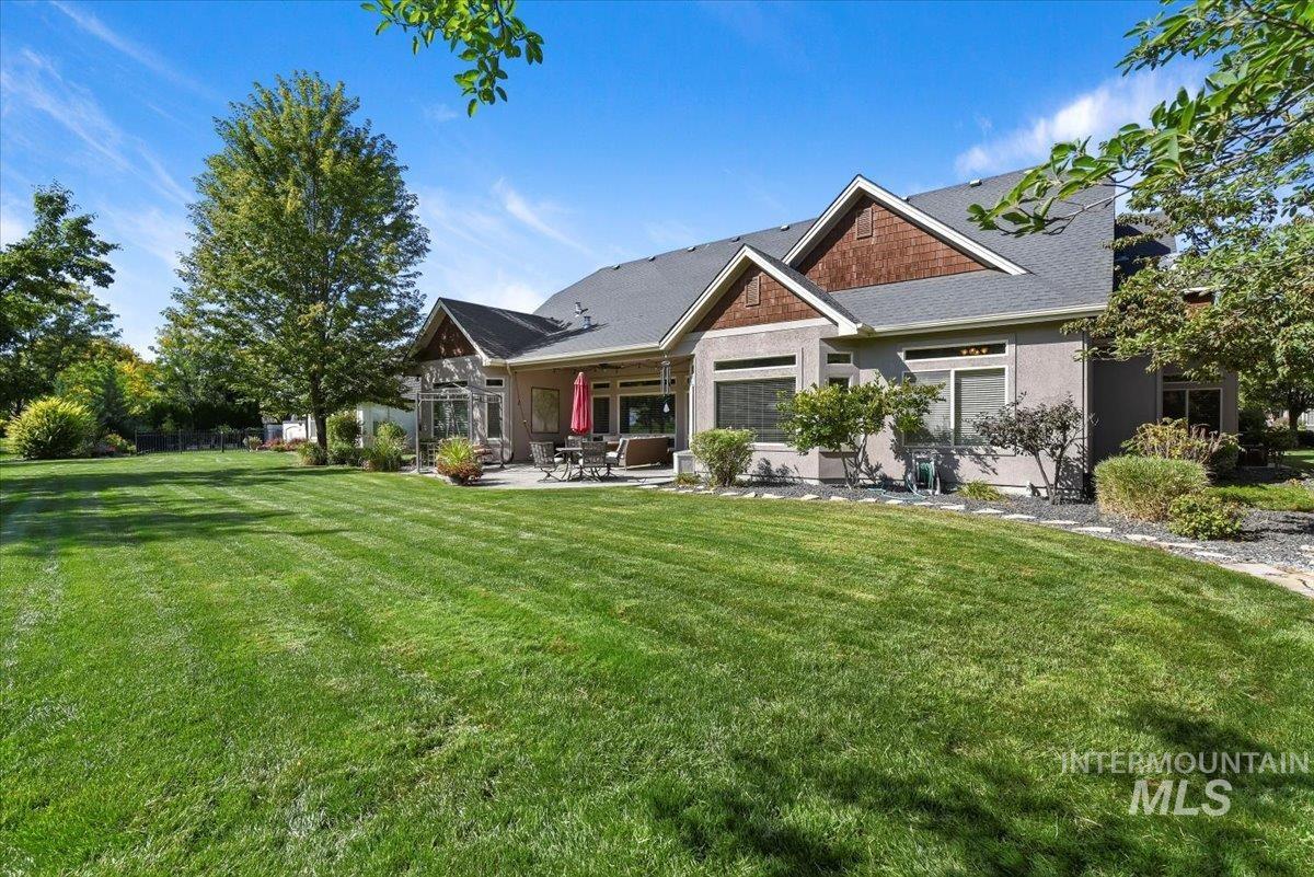 View of back of house with covered patio, lawn, and stucco siding