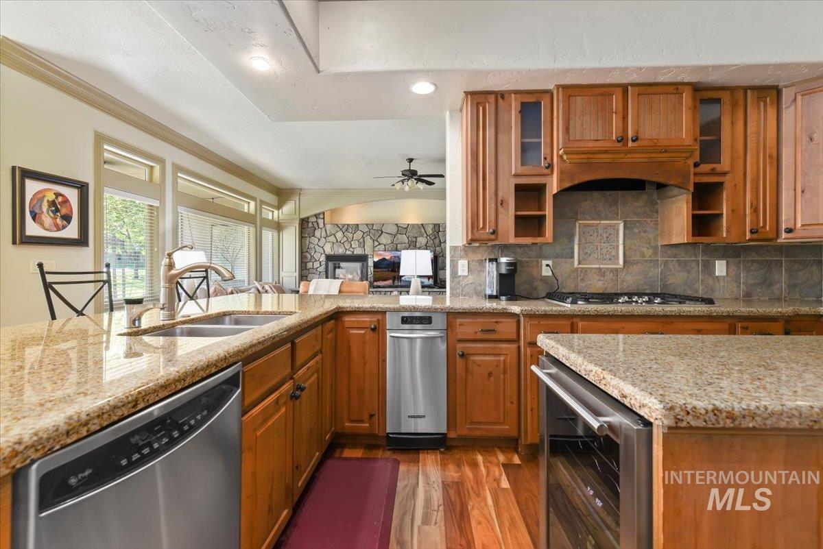 Kitchen with brown cabinets, light stone countertops, dishwasher, and recessed lighting