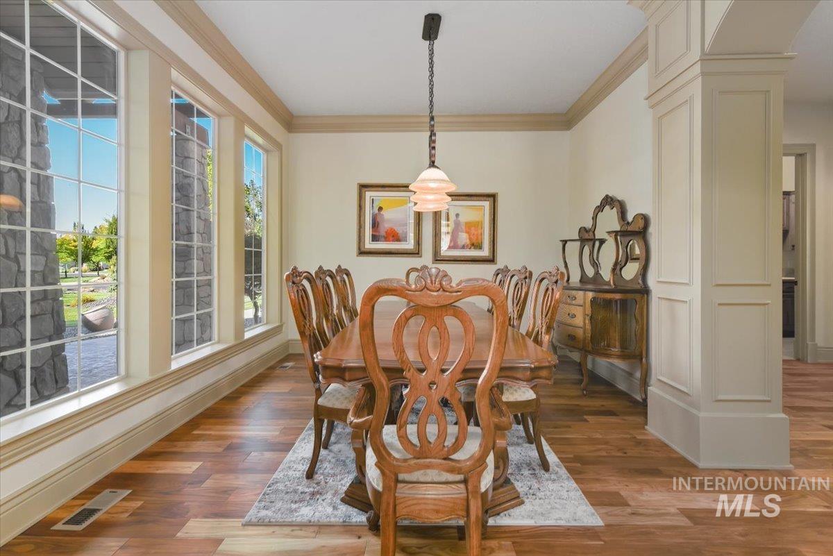 Dining room with decorative columns, crown molding, and light wood-style floors