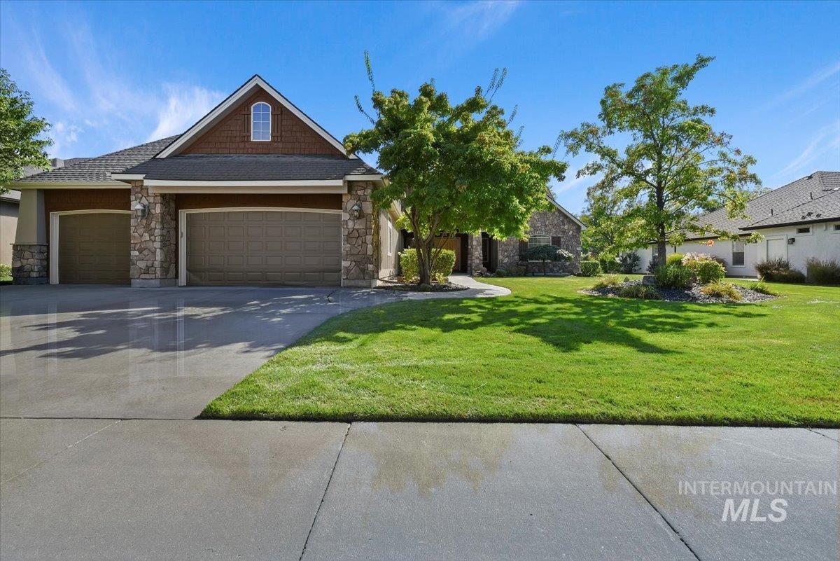 Craftsman-style home with stone siding, a garage, driveway, and a front yard