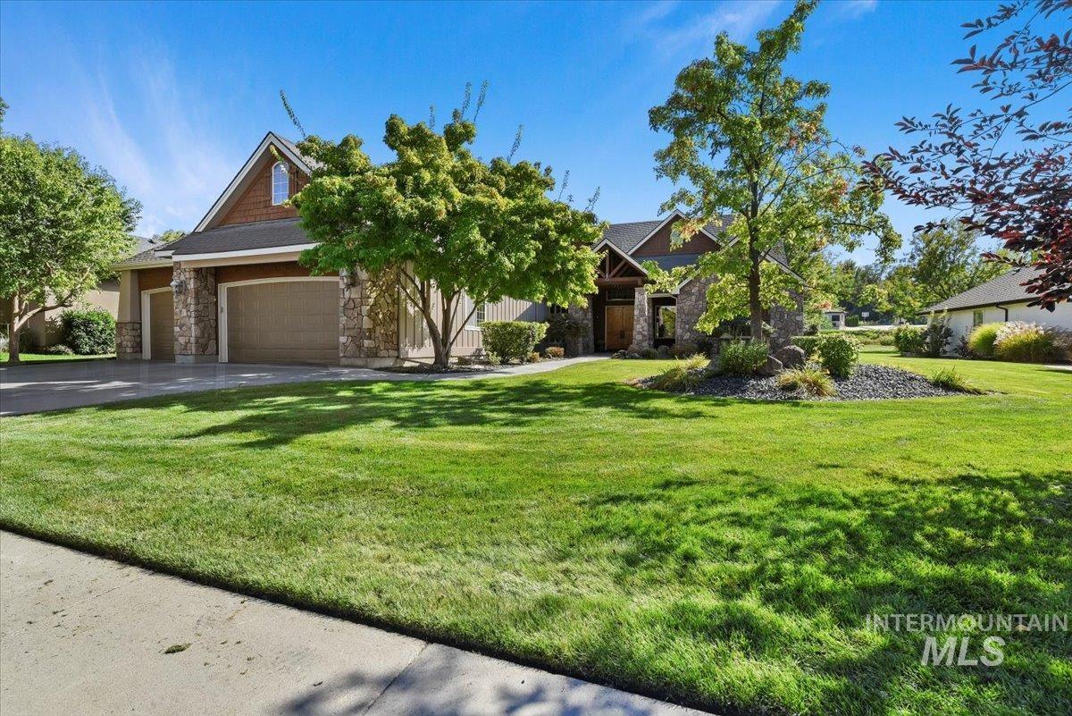 View of front of house featuring stone siding, a front yard, a garage, and driveway