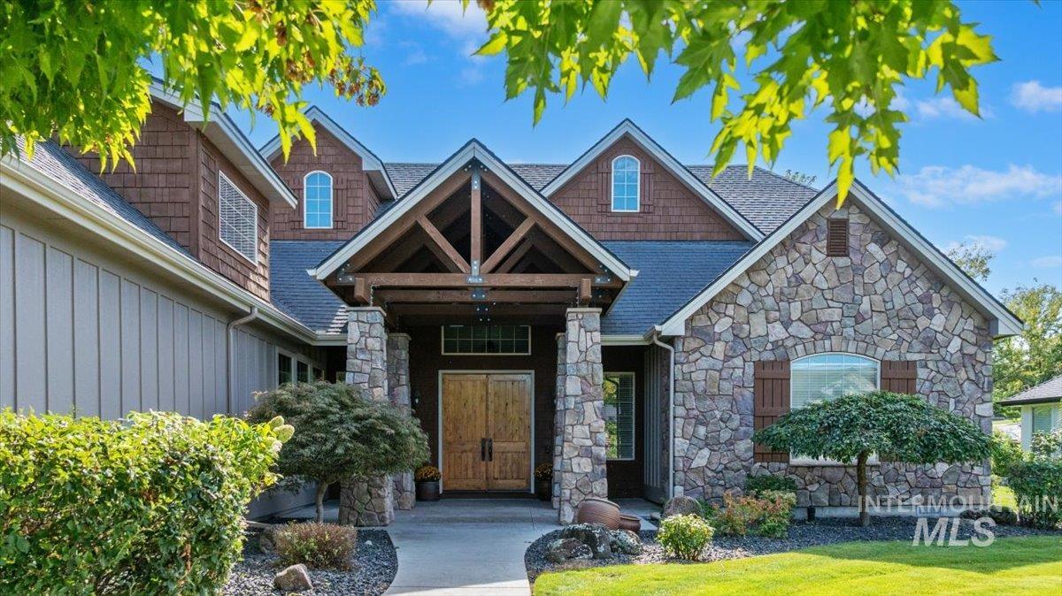 View of front of home with stone siding, board and batten siding, and a shingled roof