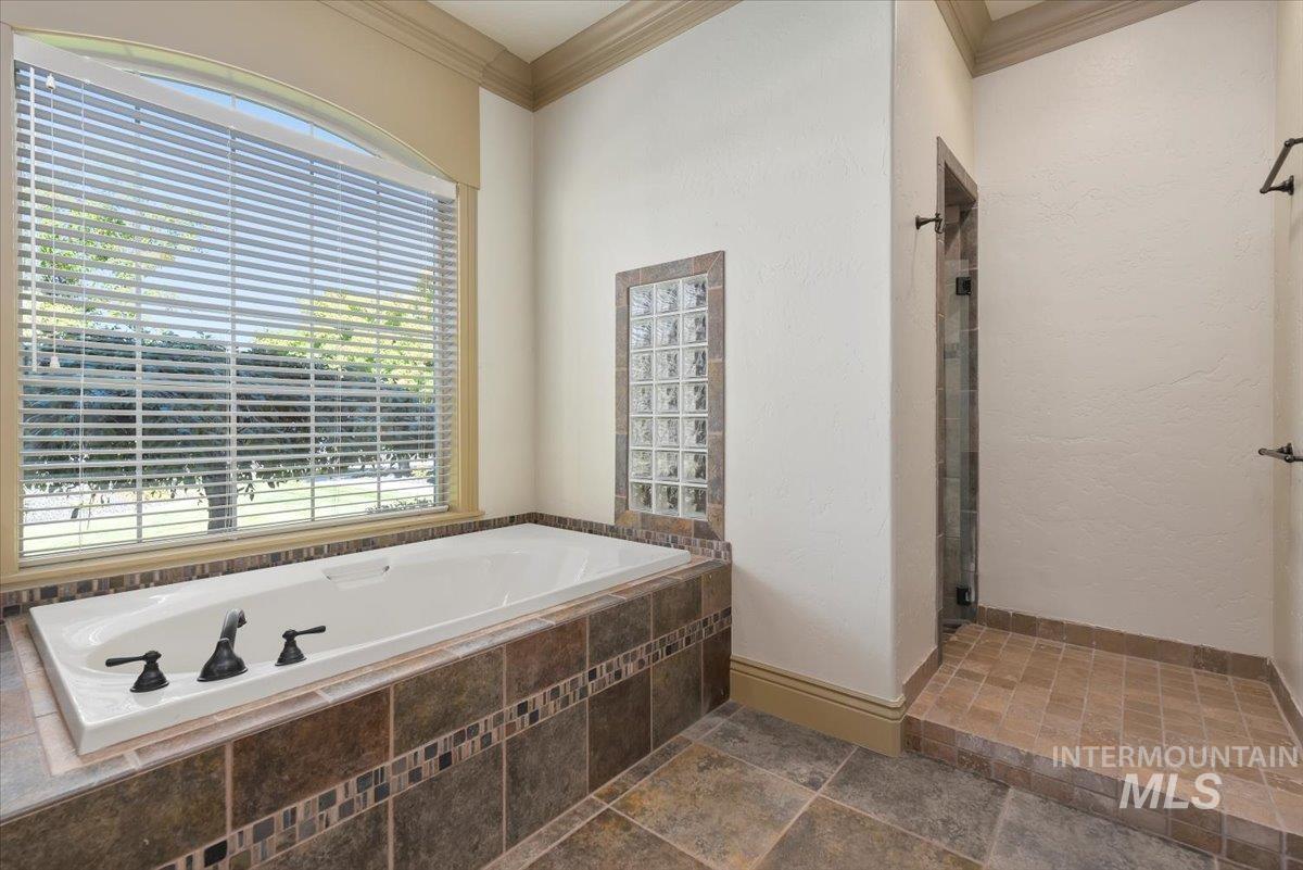 Full bathroom featuring a garden tub, ornamental molding, and tiled walk in shower
