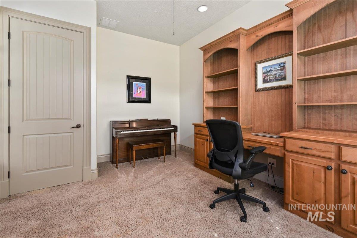 Home office with light colored carpet and a textured ceiling