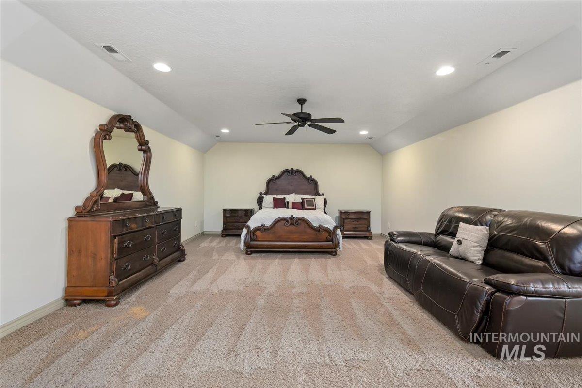 Bedroom with light carpet, lofted ceiling, ceiling fan, and recessed lighting