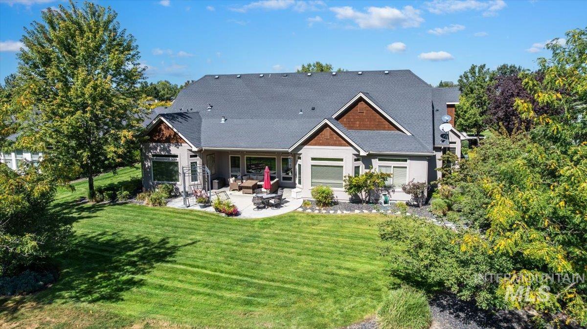 Rear view of property with a patio area, a lawn, and a shingled roof