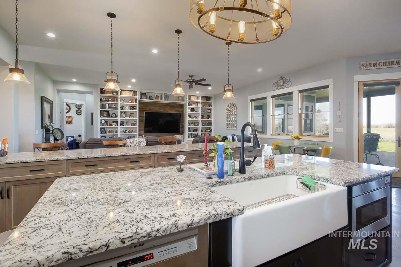 Kitchen with built in features, light stone countertops, open floor plan, stainless steel appliances, and recessed lighting