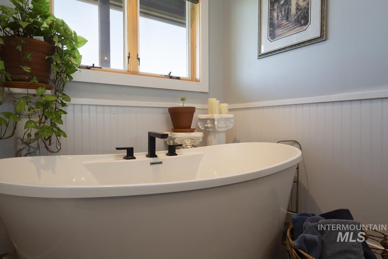 Full bathroom with a freestanding tub and a wainscoted wall