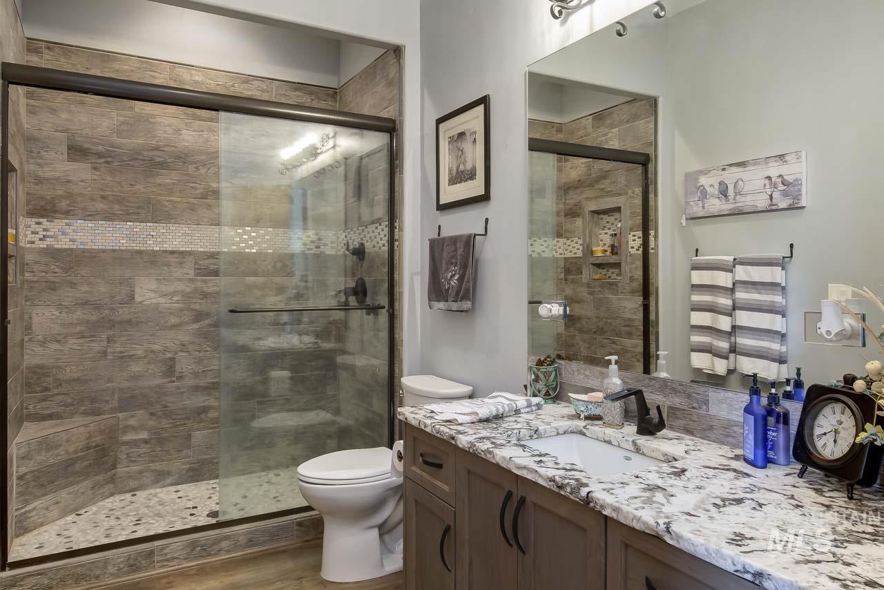Full bath with vanity, a stall shower, and dark wood-type flooring