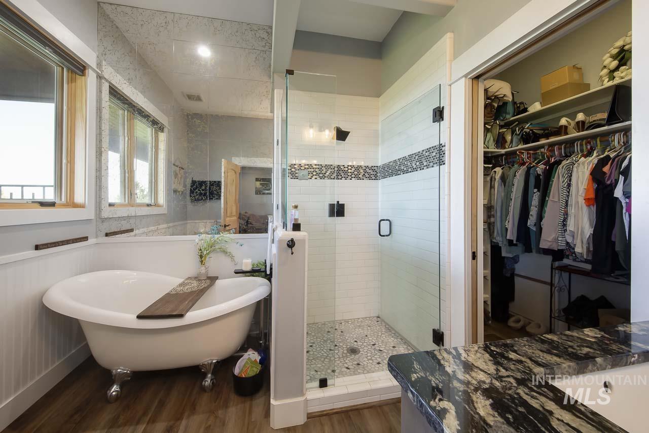 Bathroom featuring vanity, a shower stall, a freestanding bath, dark wood-style floors, and a walk in closet