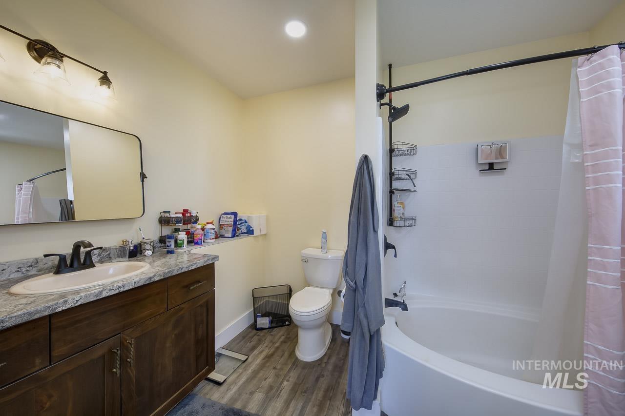 Full bathroom featuring shower / bath combination with curtain, vanity, dark wood finished floors, and recessed lighting