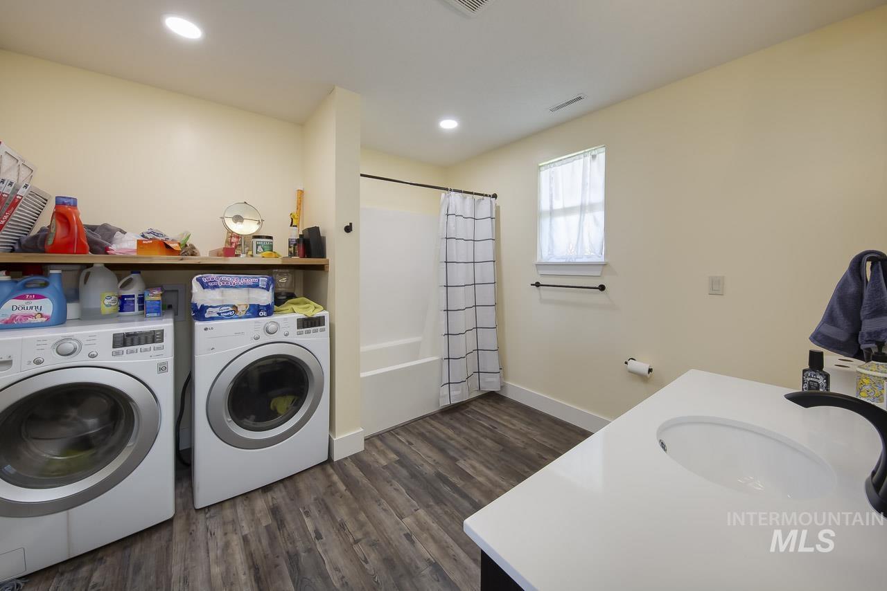 Laundry area with dark wood finished floors, washer and clothes dryer, and recessed lighting