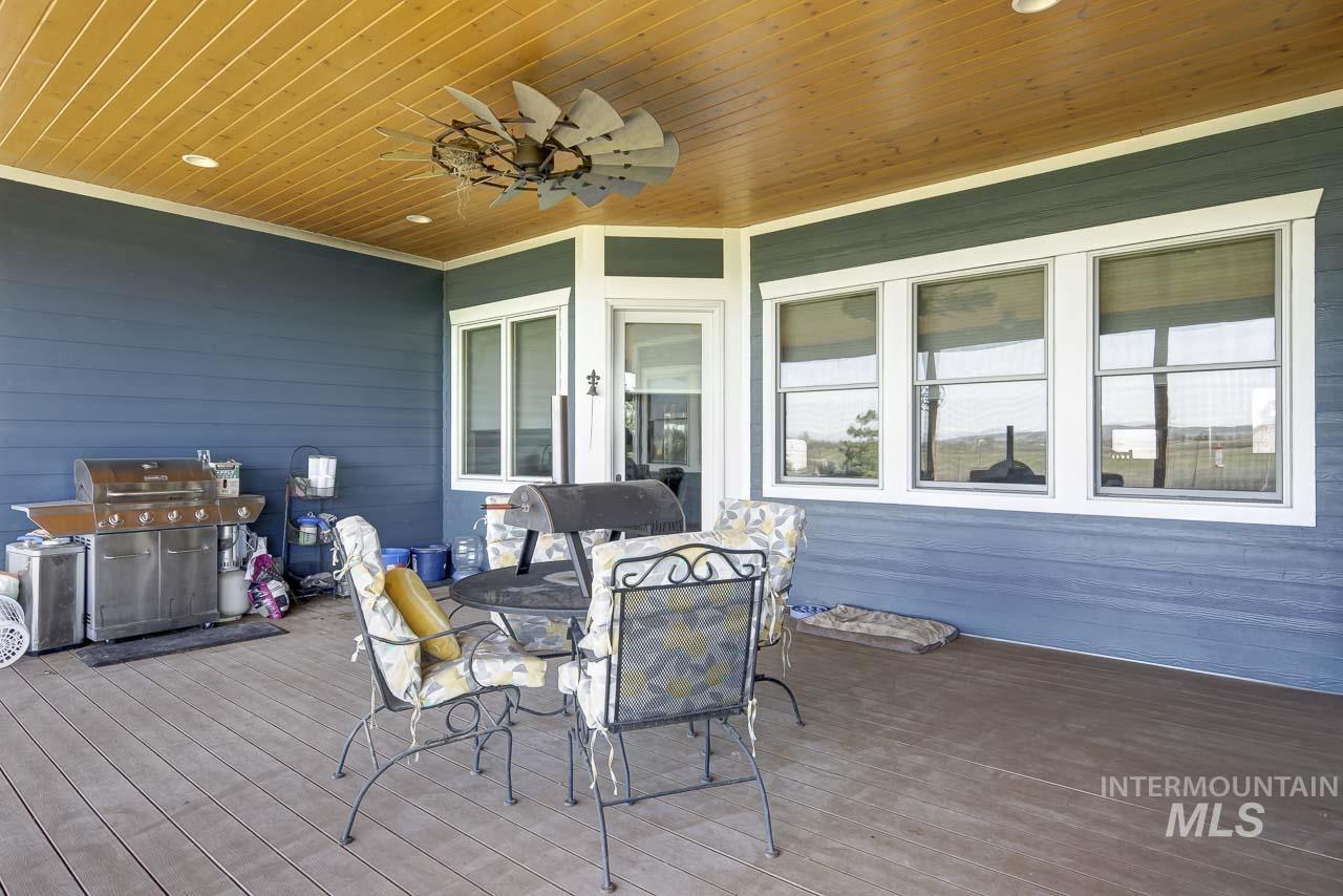 Wooden terrace with a grill, outdoor dining area, and ceiling fan