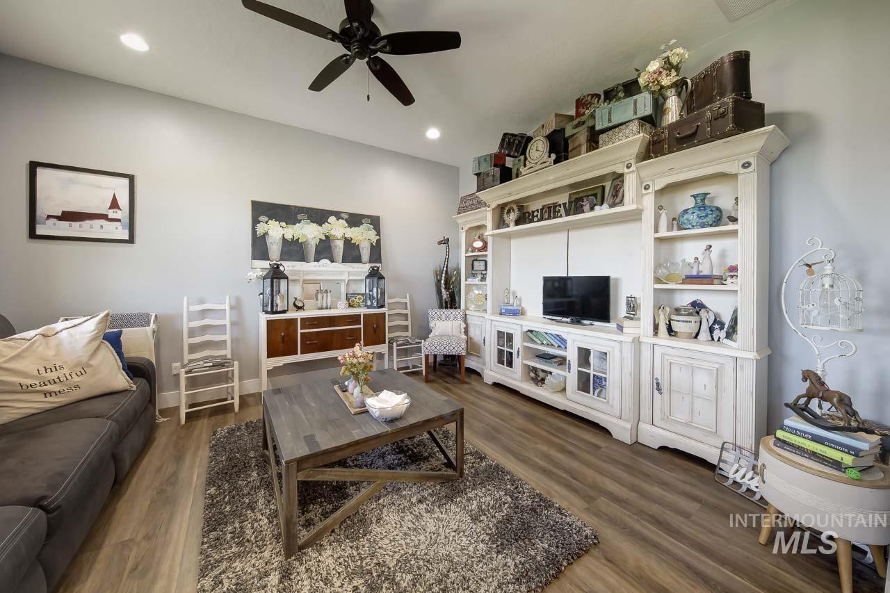 Living area with dark wood-style flooring, a ceiling fan, and recessed lighting
