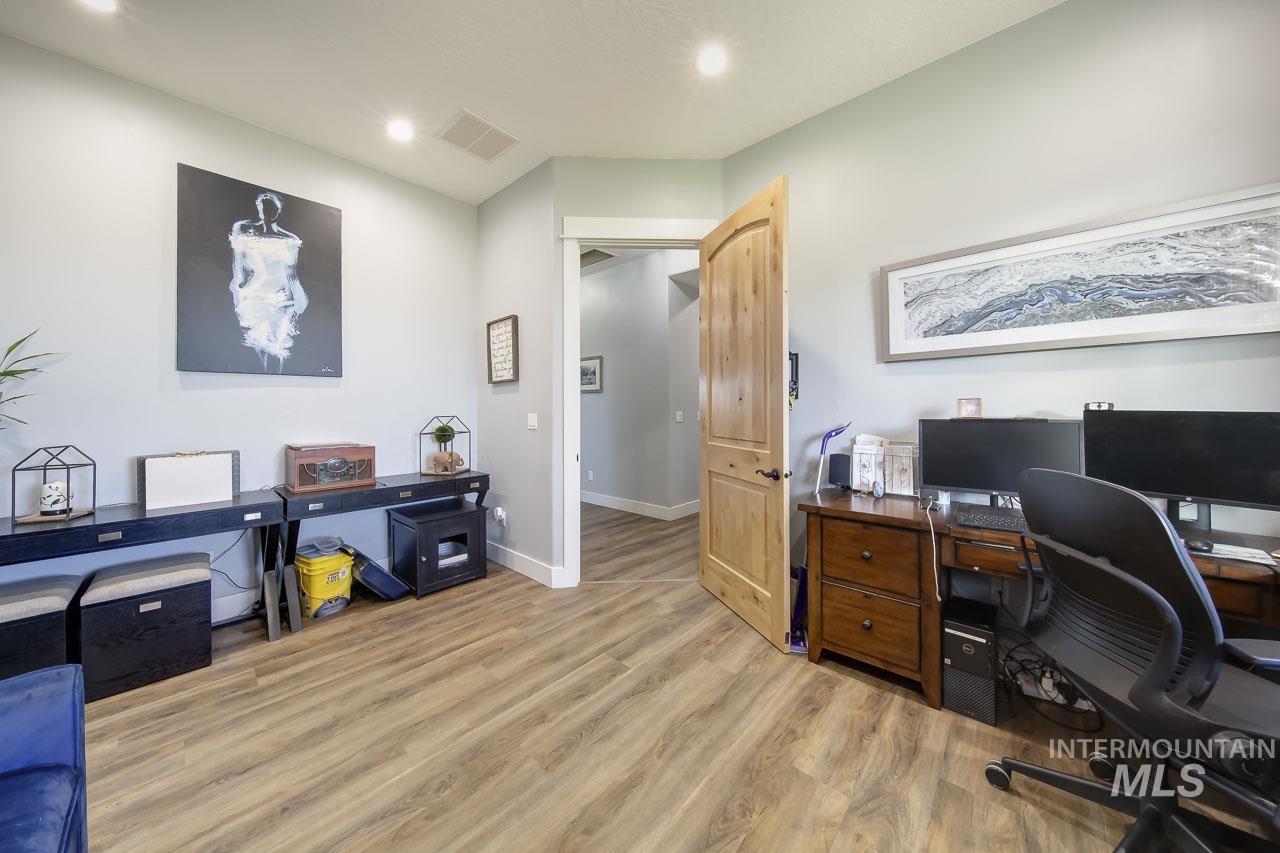 Office with light wood-type flooring and recessed lighting