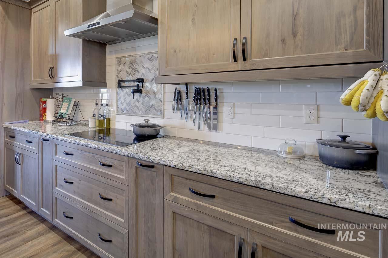 Kitchen featuring tasteful backsplash, wall chimney exhaust hood, and light stone countertops
