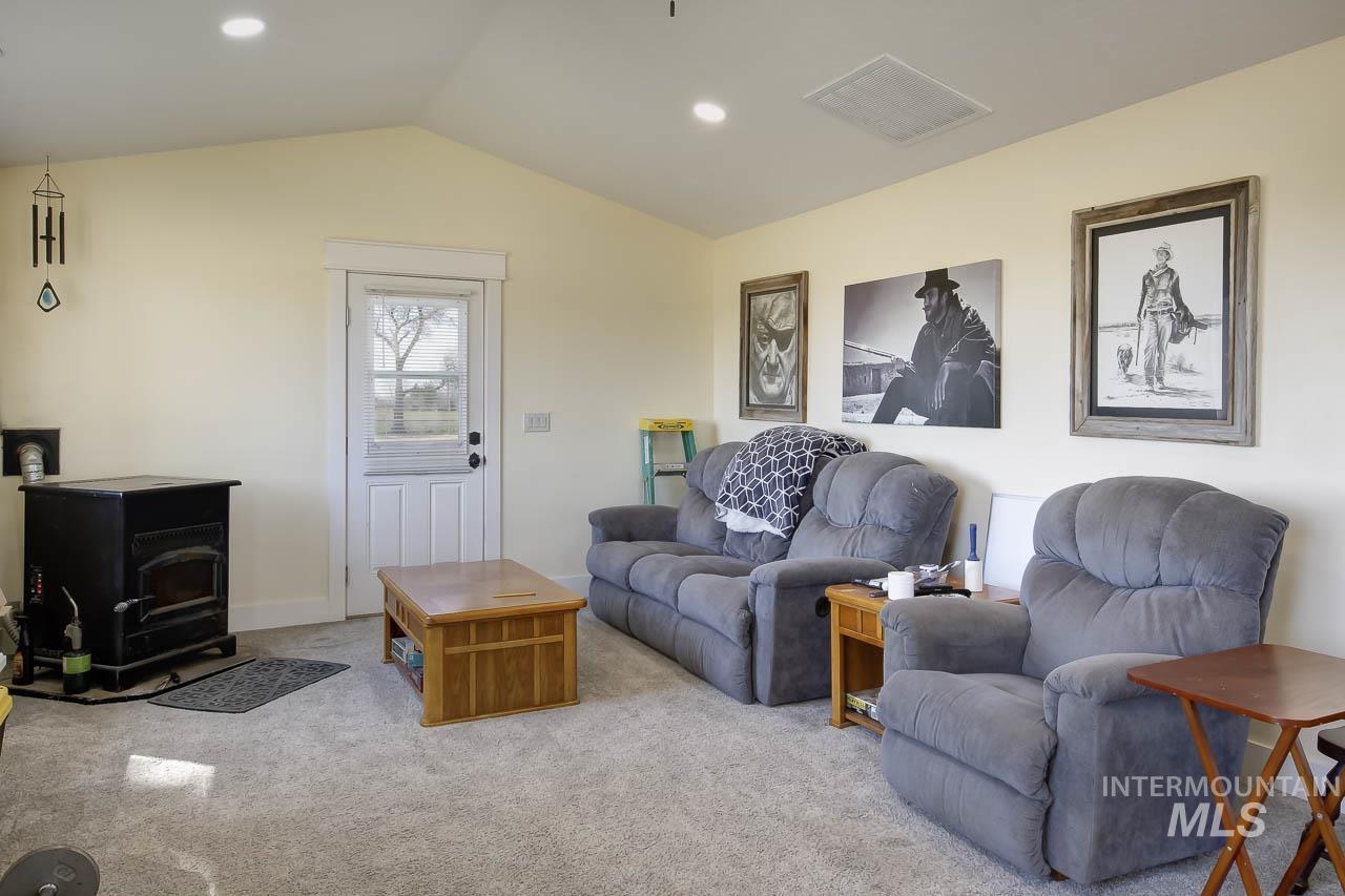 Living room featuring a wood stove, carpet floors, vaulted ceiling, and recessed lighting