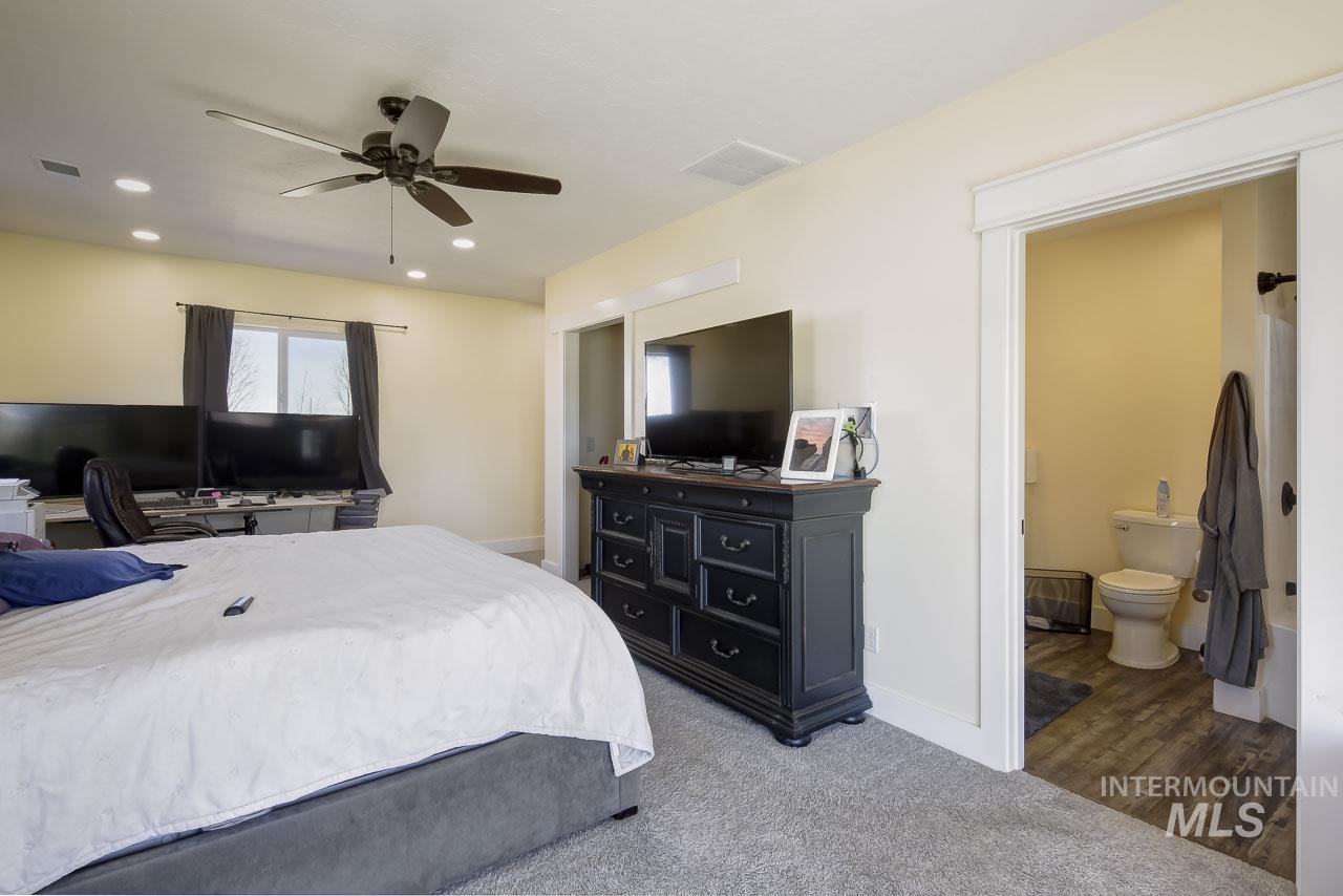 Bedroom with light colored carpet, a ceiling fan, recessed lighting, and ensuite bathroom