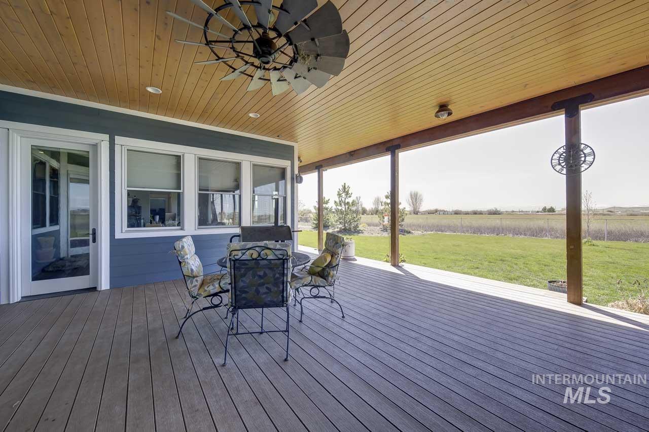 Wooden deck with a ceiling fan, outdoor dining space, a yard, and a view of rural / pastoral area