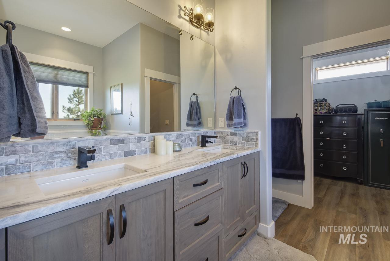 Full bath featuring double vanity, dark wood finished floors, backsplash, and a closet