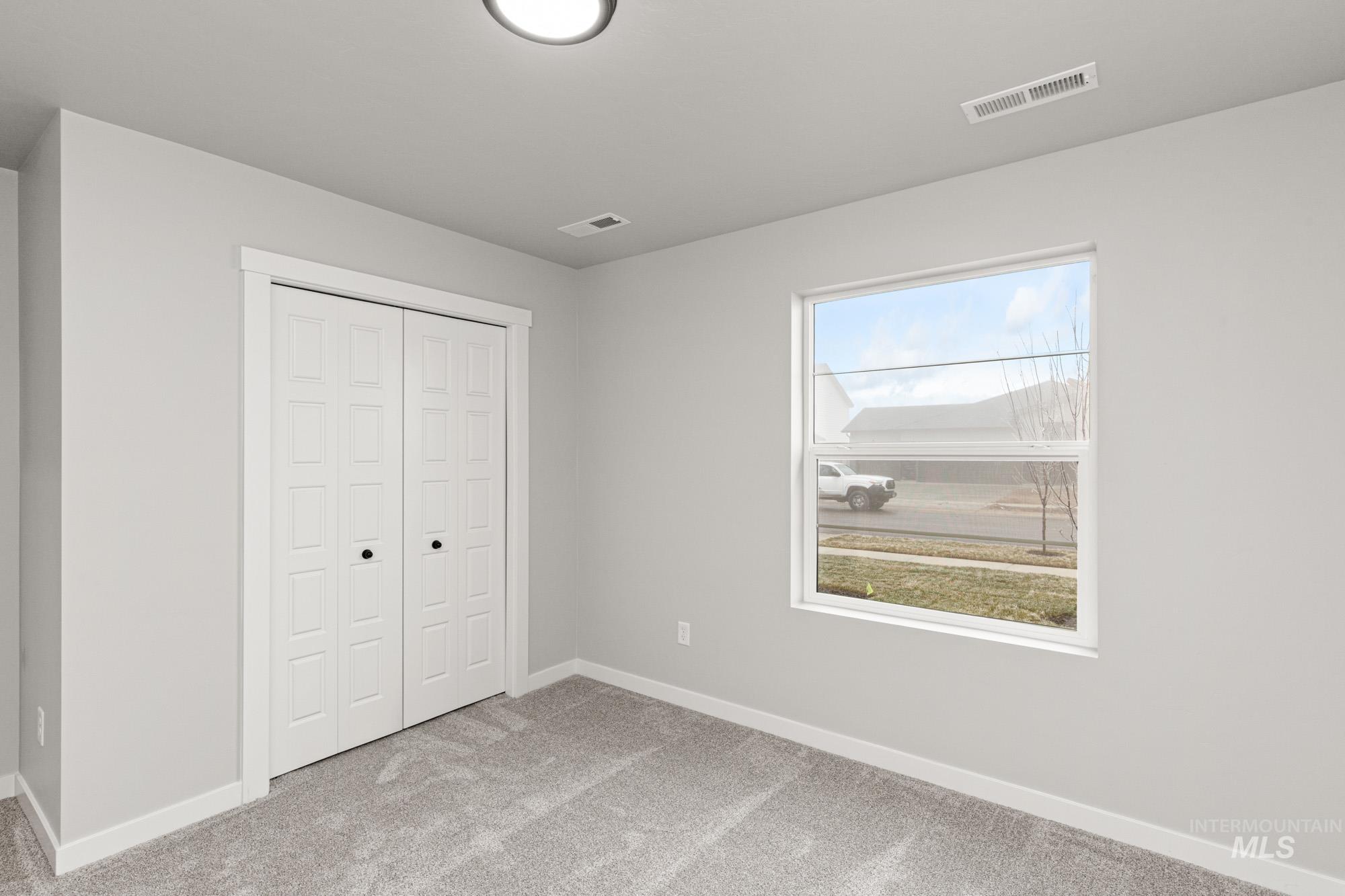 Unfurnished bedroom featuring light carpet and a closet