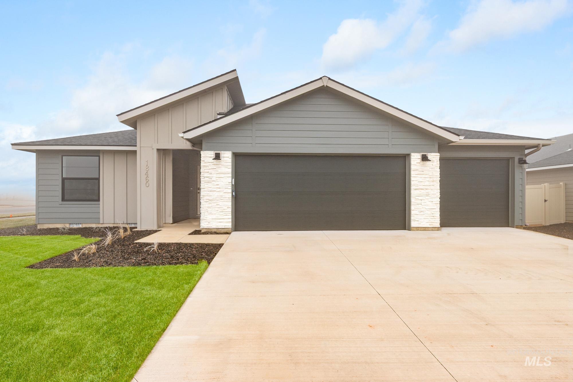 View of front of house with board and batten siding, concrete driveway, a front yard, a garage, and roof with shingles