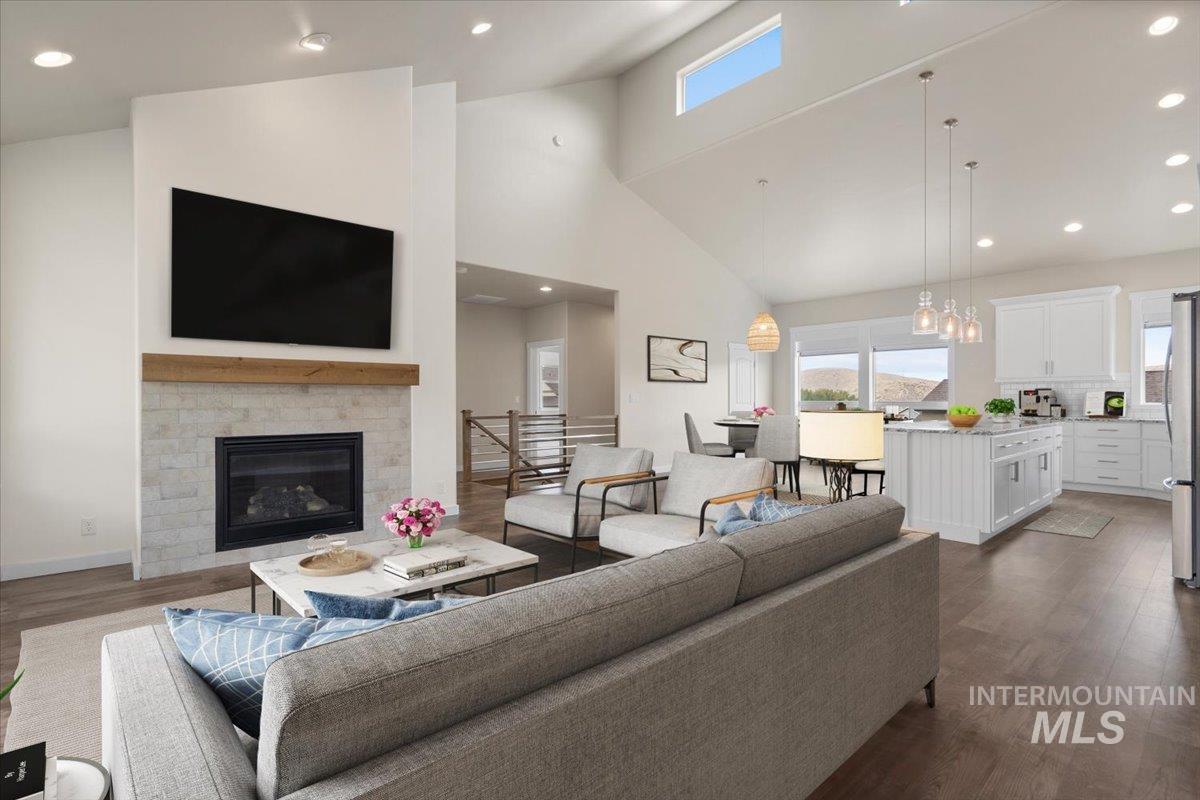 Living area with recessed lighting, high vaulted ceiling, dark wood-style flooring, and a glass covered fireplace