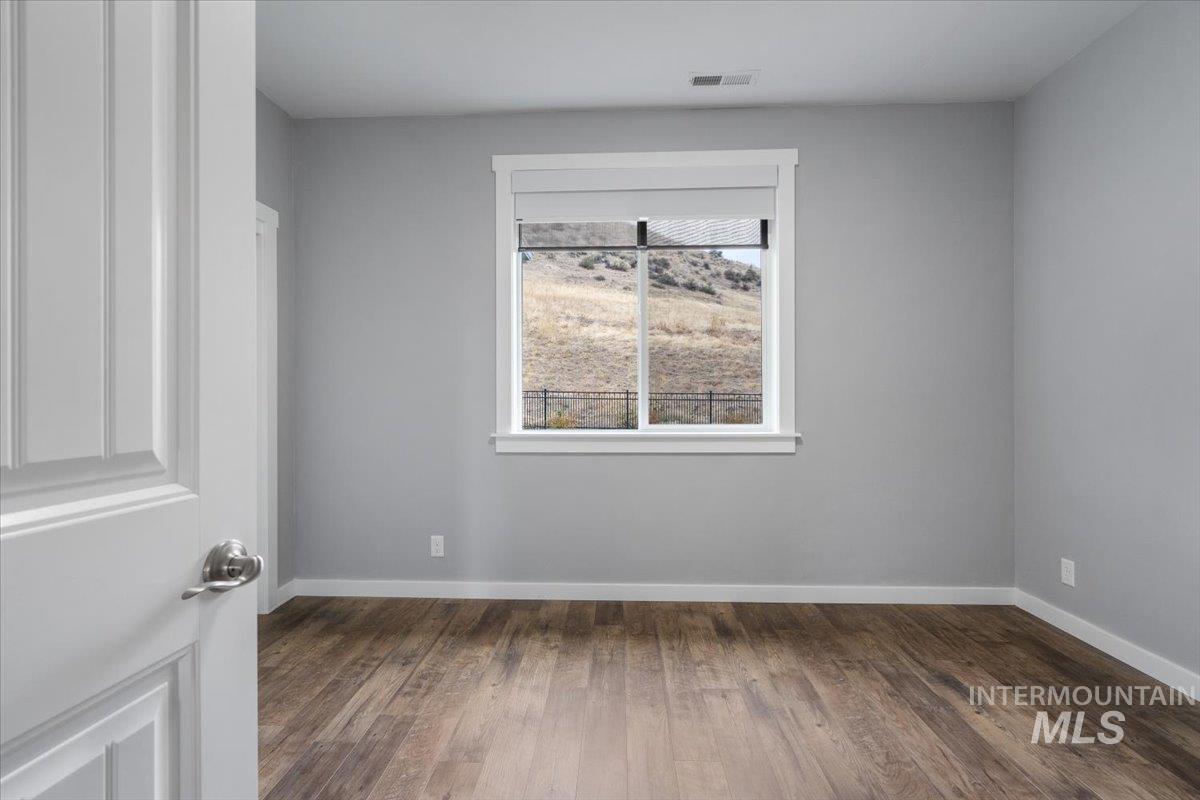 Empty room featuring dark wood finished floors and baseboards