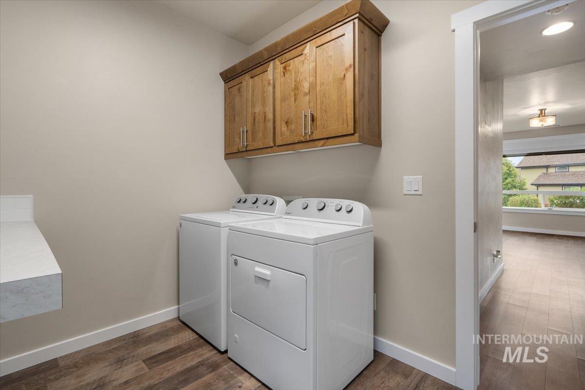 Laundry area with cabinet space, dark wood finished floors, and independent washer and dryer