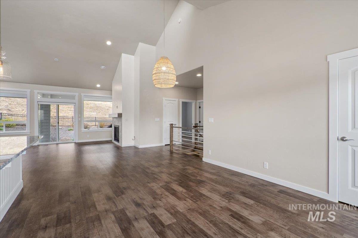 Unfurnished living room featuring high vaulted ceiling, dark wood-style floors, a fireplace, and recessed lighting