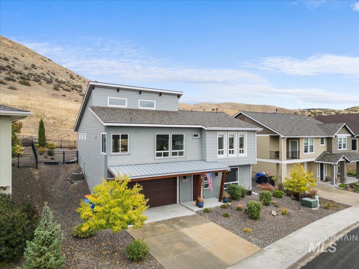 View of front of home with concrete driveway, a mountain view, a garage, a porch, and roof with shingles