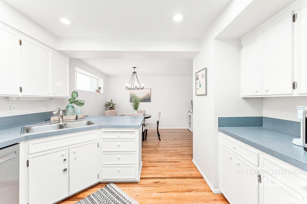Kitchen with white cabinets, light wood-style floors, dishwasher, light countertops, and recessed lighting