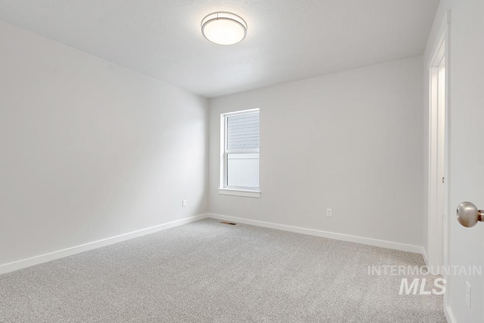 Spare room featuring light colored carpet and baseboards