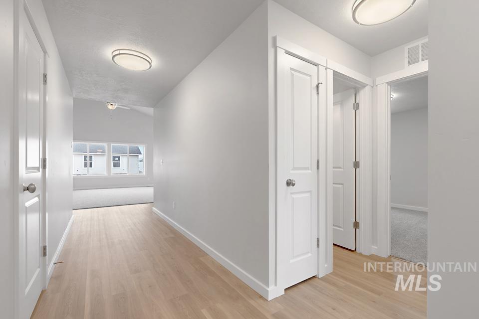 Hallway with light wood-style flooring and baseboards