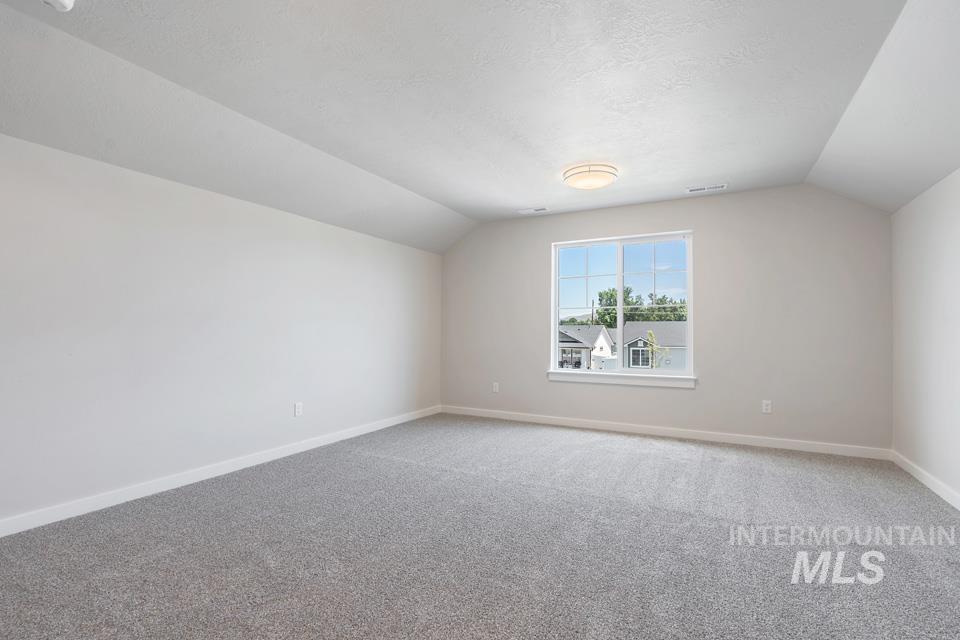 Additional living space with vaulted ceiling, carpet, and a textured ceiling
