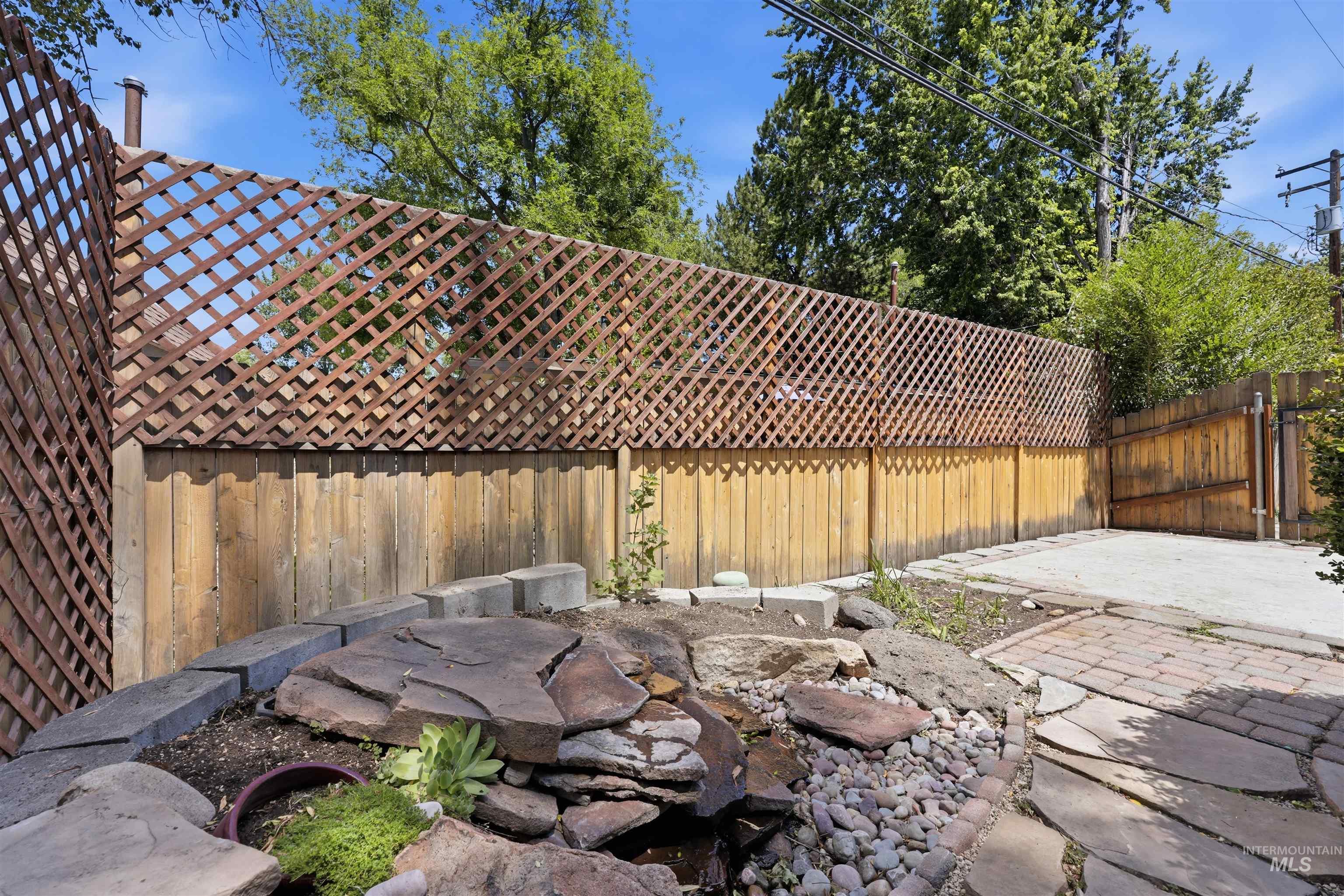 Landscaped rock garden featuring a water feature, stone pavers, and a brick pathway