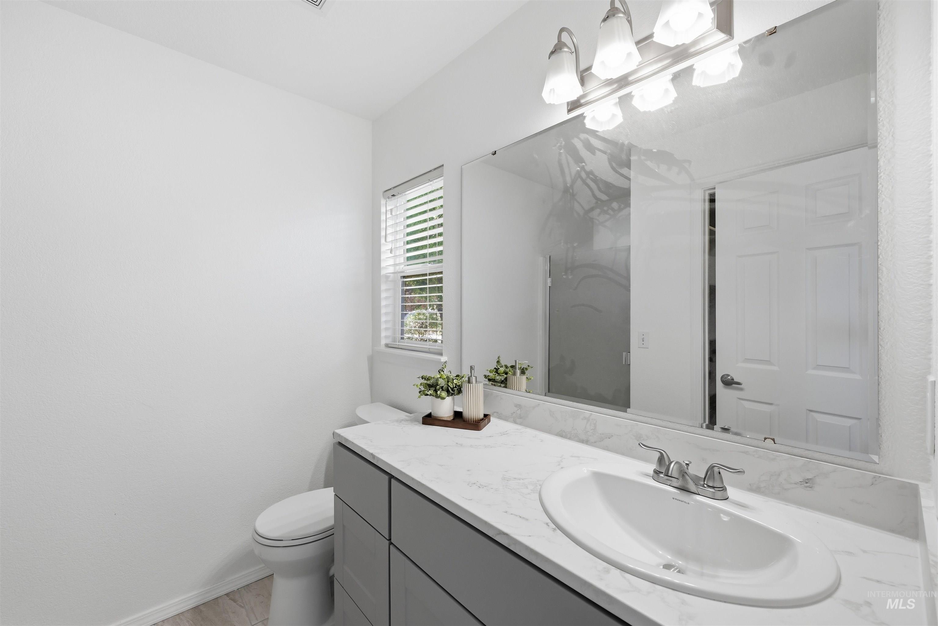 Bathroom featuring a modern gray vanity with a white countertop and integrated sink