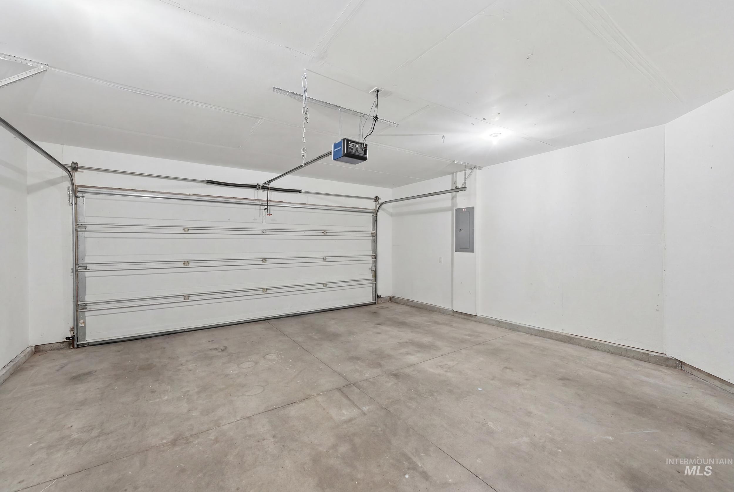 Spacious garage featuring a concrete floor, white walls, and a large sectional garage door